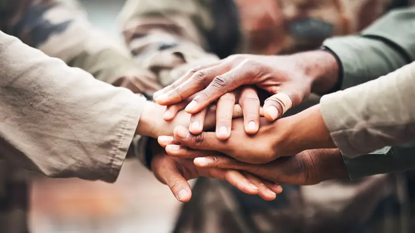 Hands stacked together showing unity, teamwork, and mutual support among people.